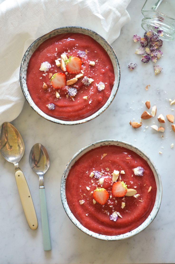 Two bowls of Chilled Strawberry-Rhubarb Soup topped with straberries and nuts