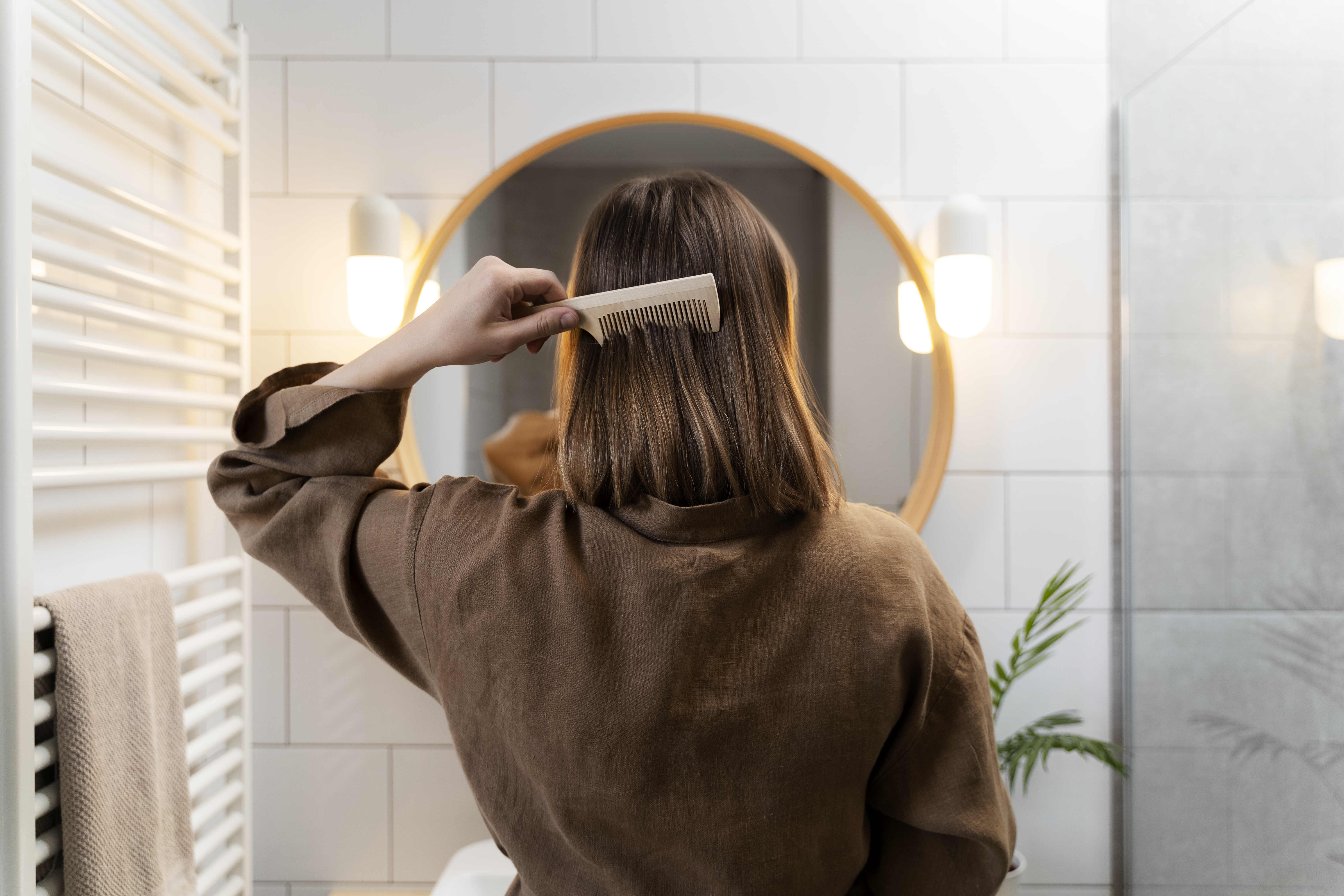 Woman combing hair in bathroom