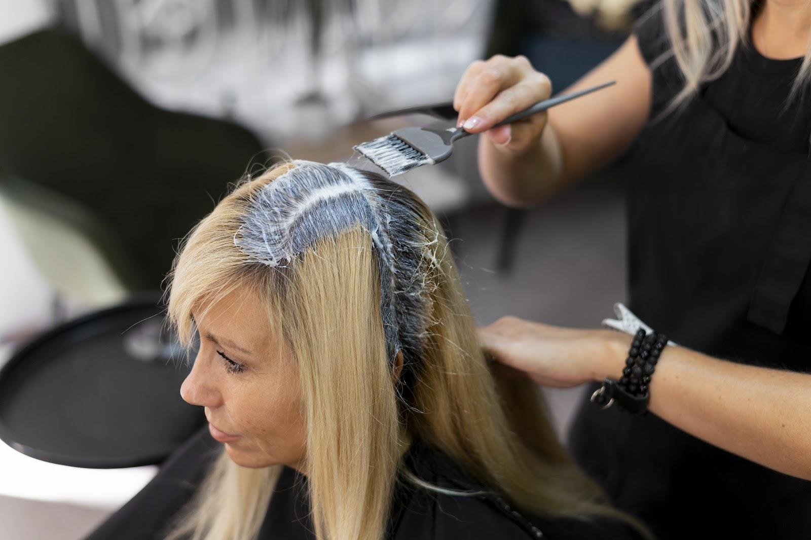 A stylist applying color on customer's hair