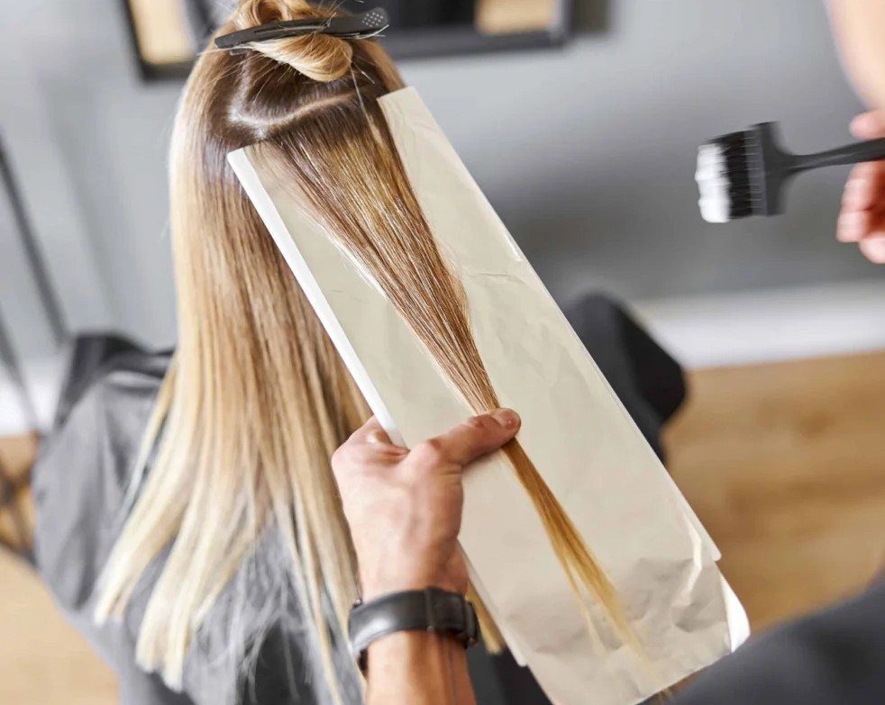 Hair stylist applying highlights foil
